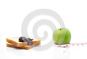 Measuring tape wrapped around a green apple with Slice of white