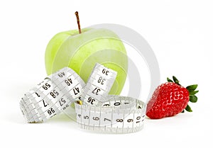 Measuring tape wrapped around a green apple and strawberry as a symbol of diet