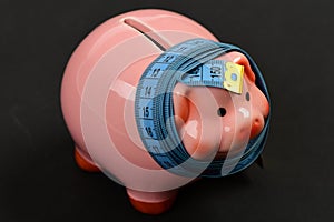 Measuring tape wrapped around piggy bank or money box