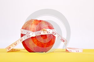 Measuring tape wrapped around a red apple