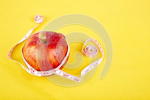 Measuring tape wrapped around a red apple