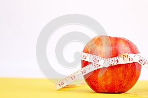 Measuring tape wrapped around a red apple