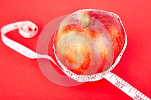 Measuring tape wrapped around a red apple