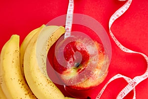 Measuring tape wrapped around a red apple and banana