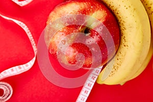 Measuring tape wrapped around a red apple and banana