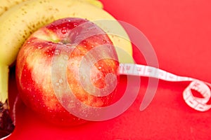 Measuring tape wrapped around a red apple and banana