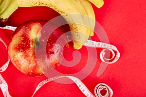 Measuring tape wrapped around a red apple and banana