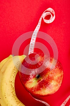 Measuring tape wrapped around a red apple and banana