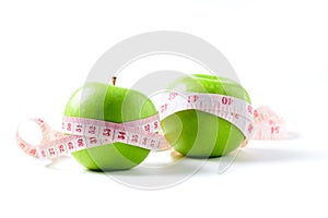 Measuring tape wrapped around two green apple isolated on white  background