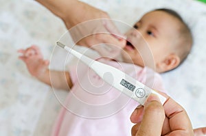 Measuring temperature of sick asian baby with digital the