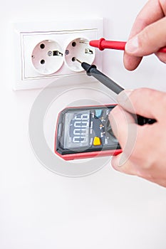 Measuring the voltage in the socket with a professional digital multimeter. Profession electrician, the process of installing