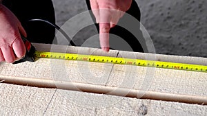 Measuring yellow tape measure scale with centimeters on wooden boards for marking the place of cutting. Lumber, house construction