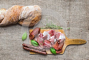 Meat appetizers selection and a loaf of rustic village bread on