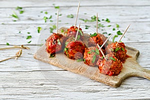 Meat balls with tomato sauce and fresh parsley on cutting board