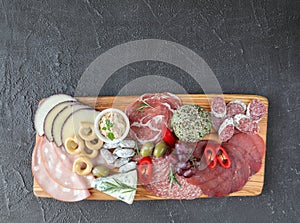 Meat board - mortadella, prosciutto, bresaola, gorgonzola, grapes, taralli, pate, red pepper, green olives, rosemary and basil on photo