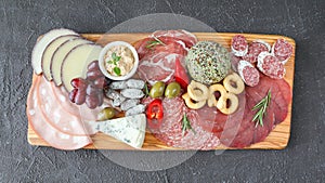 Meat board - mortadella, prosciutto, bresaola, gorgonzola, grapes, taralli, pate, red pepper, green olives, rosemary and basil on photo