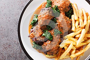 Meat for bull tail stew Rabo de toro served with french fries on white plate. Horizontal top view