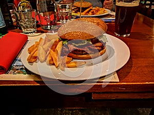 Meat burger with chips served on plate at the coveted table
