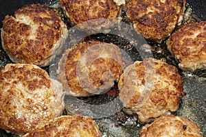 Meat burgers or cutlet-shaped patty being shallow fried in oil on a frying pan, close up. Russian kotlety