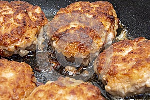 Meat burgers or cutlet-shaped patty being shallow fried in oil on a frying pan, close up. Russian kotlety