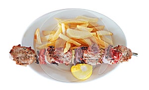 Meat called souvlaki and potatoes with lemon in plate