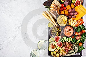 Meat and cheese appetizer platter. Sausage, cheese, hummus, vegetables, fruits and bread on black tray
