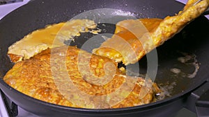 A meat chop is fried in a pan. A pork dish is prepared in the kitchen. Food fried in oil and butter and fat.