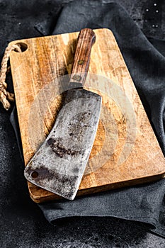 Meat cleaver on old scratched wooden cutting Board. Dark background. Top view