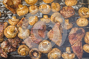 Meat cooking with field mushrooms outdoor on smouldering carbons