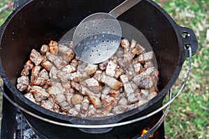 Meat is cooking in the pot, meat on the fire for rice pilau outdoors