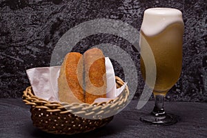 Meat croquettes served in a basket with a glass of beer