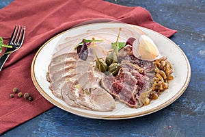 Meat delicatessen snack plate with roast beef, ham and boiled pork on red blue background