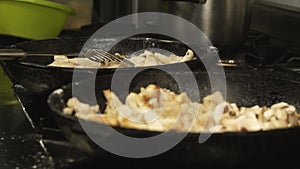 Meat dish is cooked or fried in pan or skillet in restaurant kitchen on gas stove in slow motion. Cook fries Pieces of