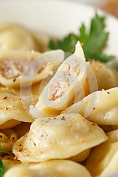 Meat dumplings - russian pelmeni, ravioli with meat on a white plate on a wooden board