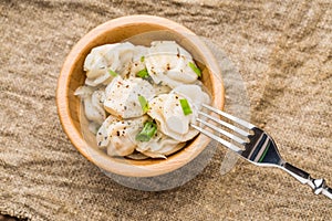 Meat dumplings - russian pelmeni, ravioli with meat on a wooden plate