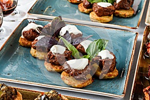 Meat fillet canapes with cream cheese and basil in plate on banquet table. Catering food, appetizer platter and snacks