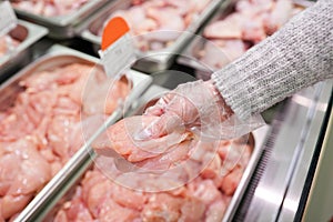Meat in food store . Woman choosing fresh chicken meat in supermarket