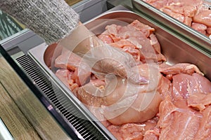 Meat in food store . Woman choosing fresh chicken meat in supermarket