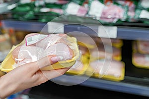 Meat in food store . Woman choosing packed fresh chicken meat in supermarket