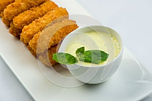 Meat fried in batter with dill in squared plate over white background