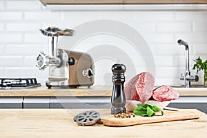 Meat grinder with fresh meat on a wooden table in kitchen interior