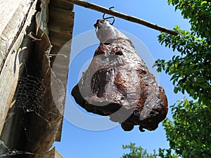 Meat. Homemade ham hanging on a hook. Dried smoked pork. Rustic food. Folk recipe. Turban, Fruska Mountain, Serbia. Home meat