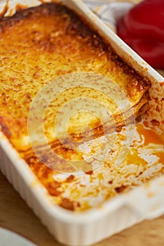 Meat lasagna with tomato sause and melted cheese in white baking dish