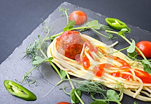 Meat meatballs and spaghetti with herbs were served as a comet with a tail on a basalt plate