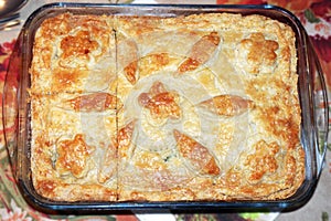 Meat pie with golden crust, decorated with ornament of dough, cools in glass baking dish, in which it was prepared. cuts for