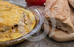 Meat pie with mushrooms and vegetables and cheese and long loaf on cut board on the table