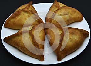 Meat pies on a white plate. Belyashi. Delicious meat pies on a black background