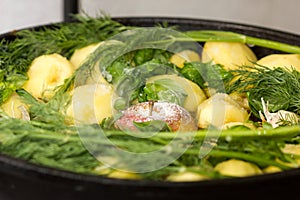 Meat with potatoes, apples and garlic in a cauldron on fire