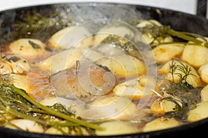 Meat with potatoes, apples and garlic in a cauldron on fire