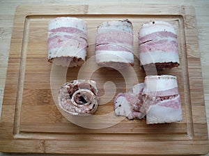meat rolls in bacon on a wooden table, the cooking process